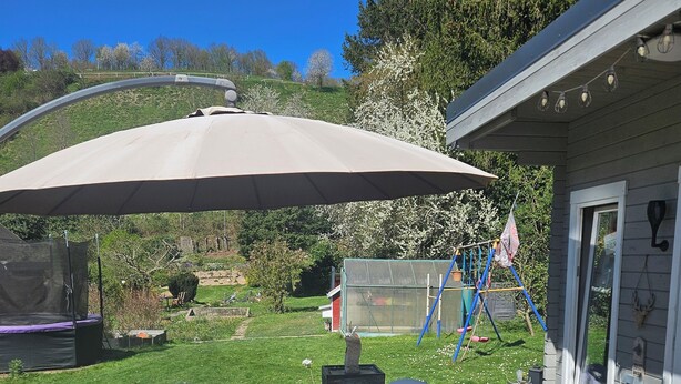 An outdoor patio with white plastic chairs and a large umbrella. - Vacation home Ewergass in Mertesdorf - only 8 km from Trier + public transport ticket from 04-26 (Mertesdorf)