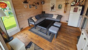 A cozy cabin interior with a gray sofa, a small table, and a refrigerator. - Vacation home Ewergass in Mertesdorf - only 8 km from Trier + public transport ticket from 04-26 (Mertesdorf)