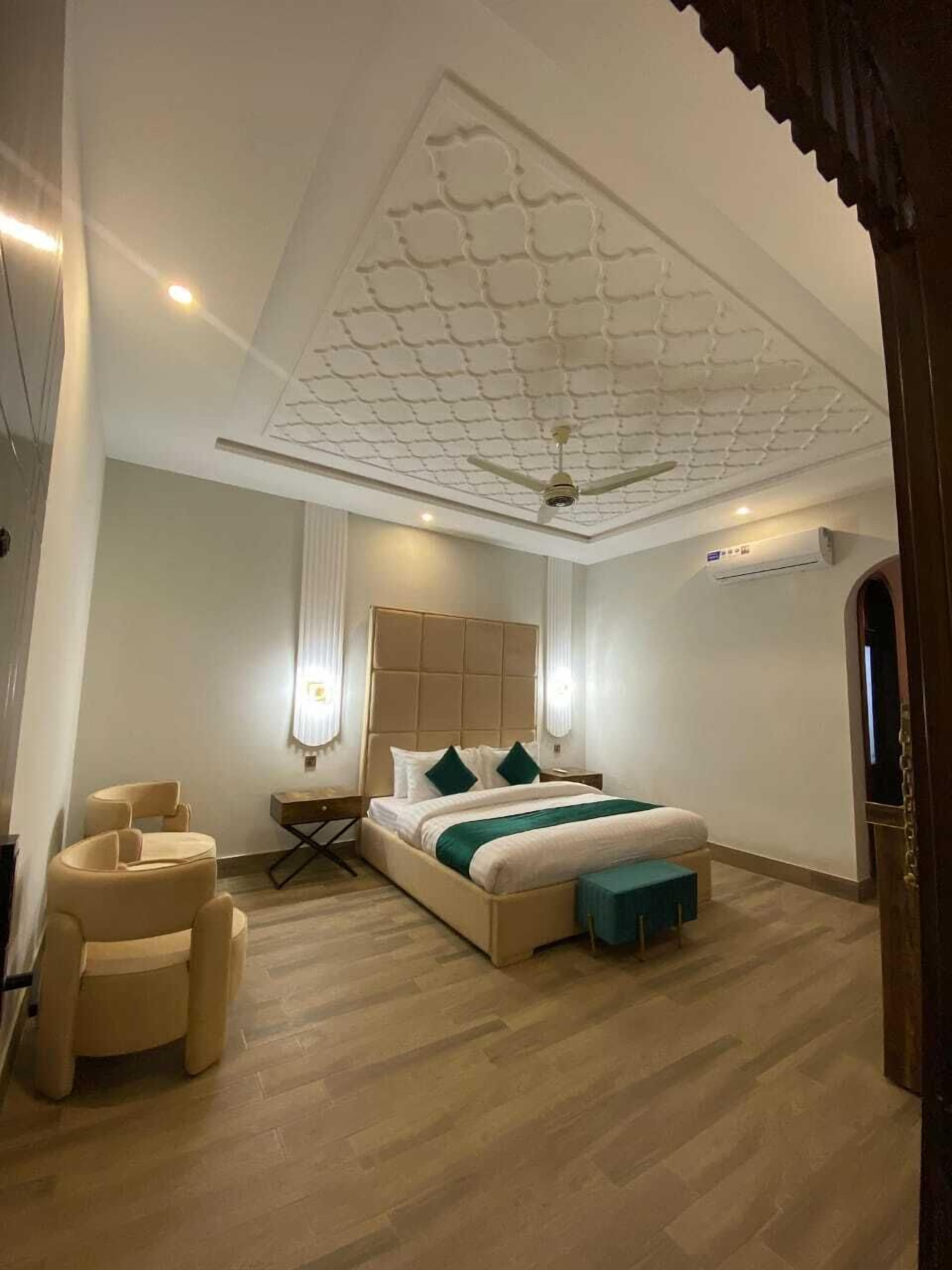 Une chambre avec un grand lit, un ventilateur de plafond et un plancher en bois.