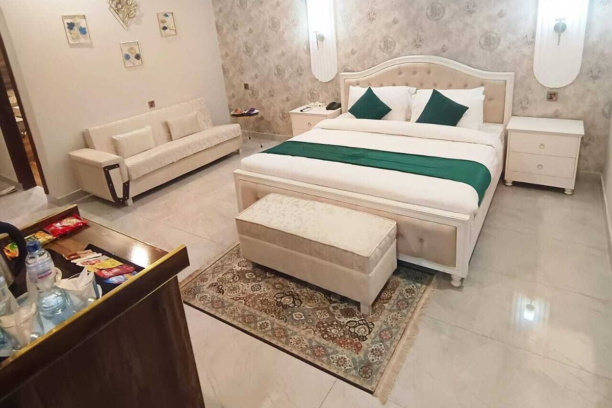 A bedroom with a bed, a nightstand, a dresser, a sofa, and a ceiling fan.