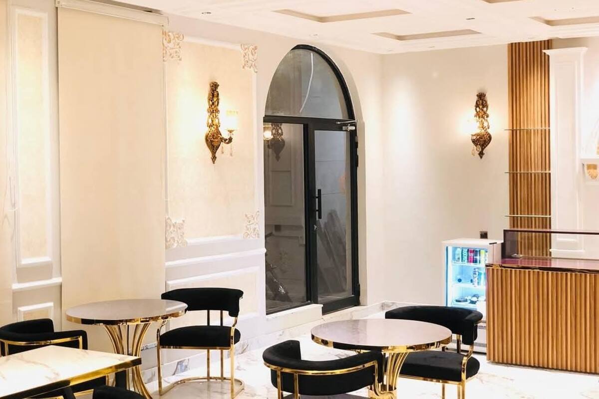 A modern hotel lobby with marble flooring, black and gold furniture, and a reception desk.