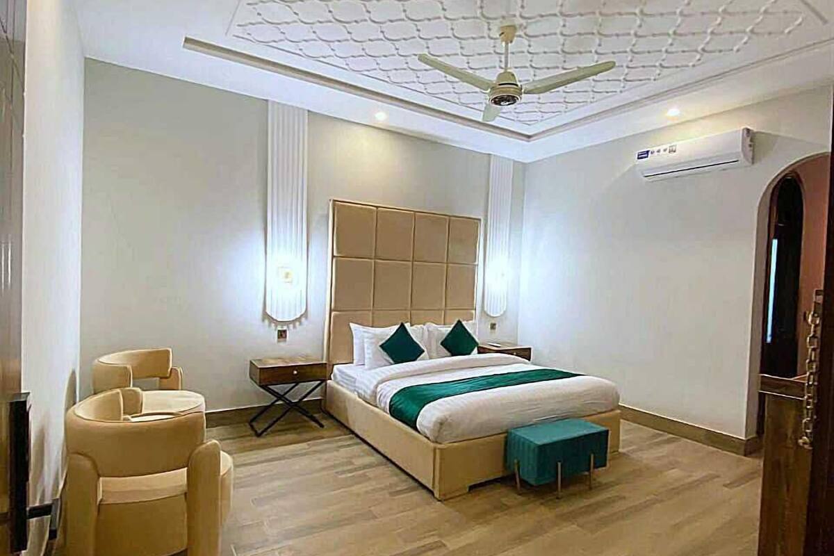 A bedroom with a large bed, a ceiling fan, and a wooden floor.
