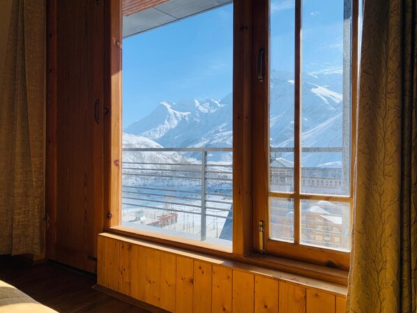 Una habitación con un amplio ventanal que ofrece vistas a montañas nevadas y un cielo azul despejado.