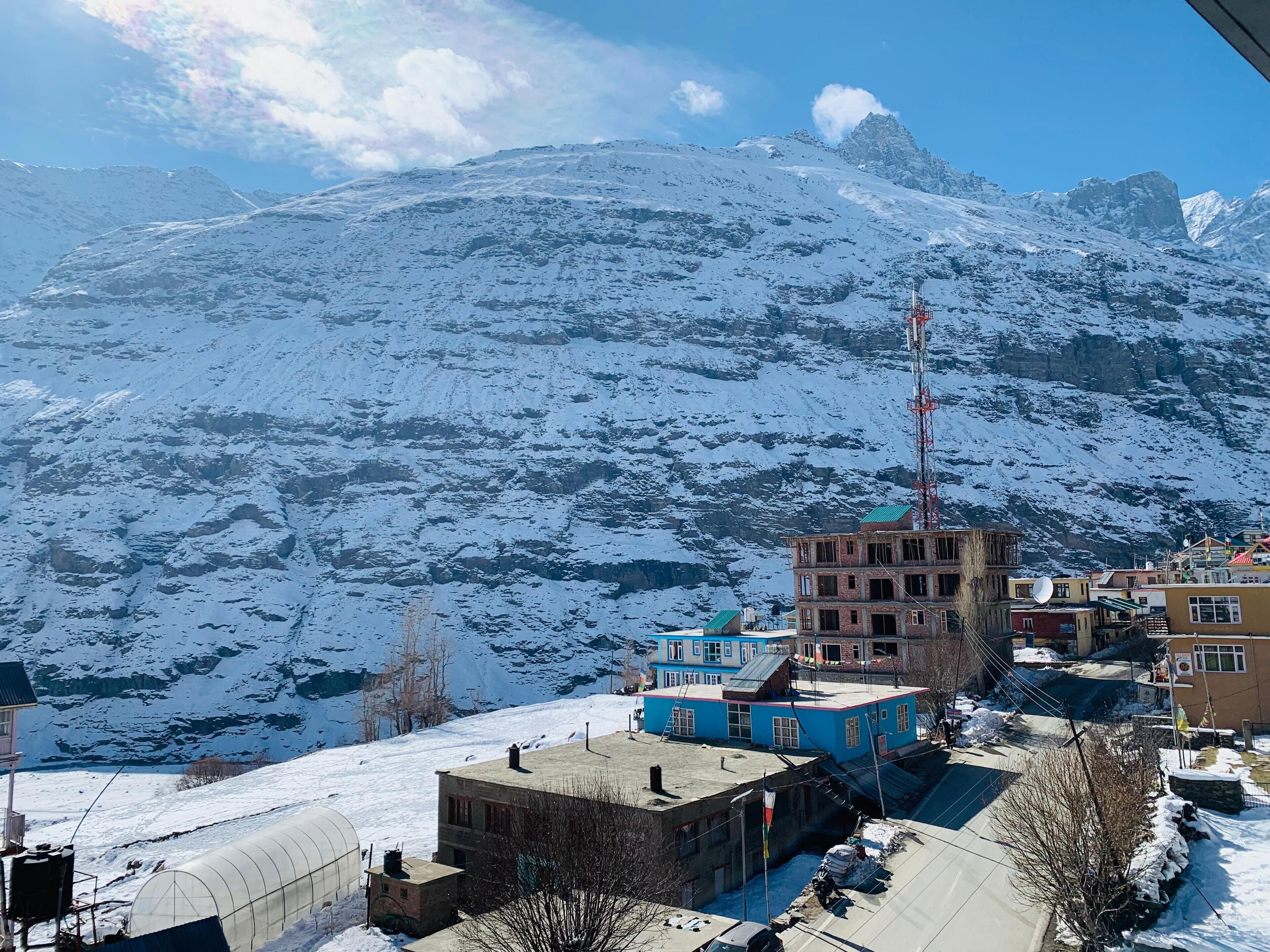 A snow-covered mountainous area with buildings, including a blue two-story structure and a brick building.