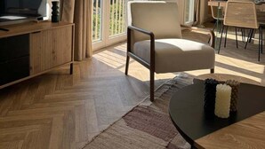A modern living room with a TV, a sofa, a dining table with chairs, and a balcony with curtains. - Le Mathurin - Wonderful 4 rooms. (Saint-Brieuc)