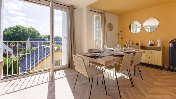 A dining area with a table set for four, large windows, and a view of the cityscape. - Le Mathurin - Wonderful 4 rooms. (Saint-Brieuc)