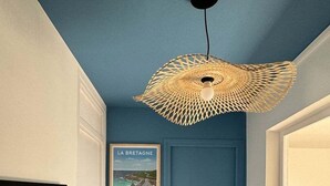 A hallway with a blue door, a poster of La Bretagne, and a woven ceiling light fixture. - Le Mathurin - Wonderful 4 rooms. (Saint-Brieuc)