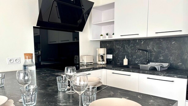 Eine moderne Küche mit weißen Schränken, einer schwarzen Arbeitsplatte und einem eingebauten Backofen.