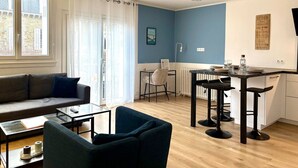 Ein modernes Wohnzimmer mit einer Couch, einem Glastisch und einem Essbereich mit Tisch und Stühlen.