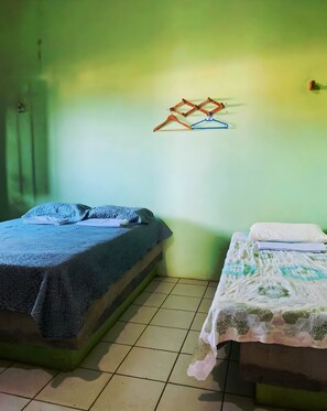 Two single beds with different bedding styles, a wall-mounted hanger, and a tiled floor.