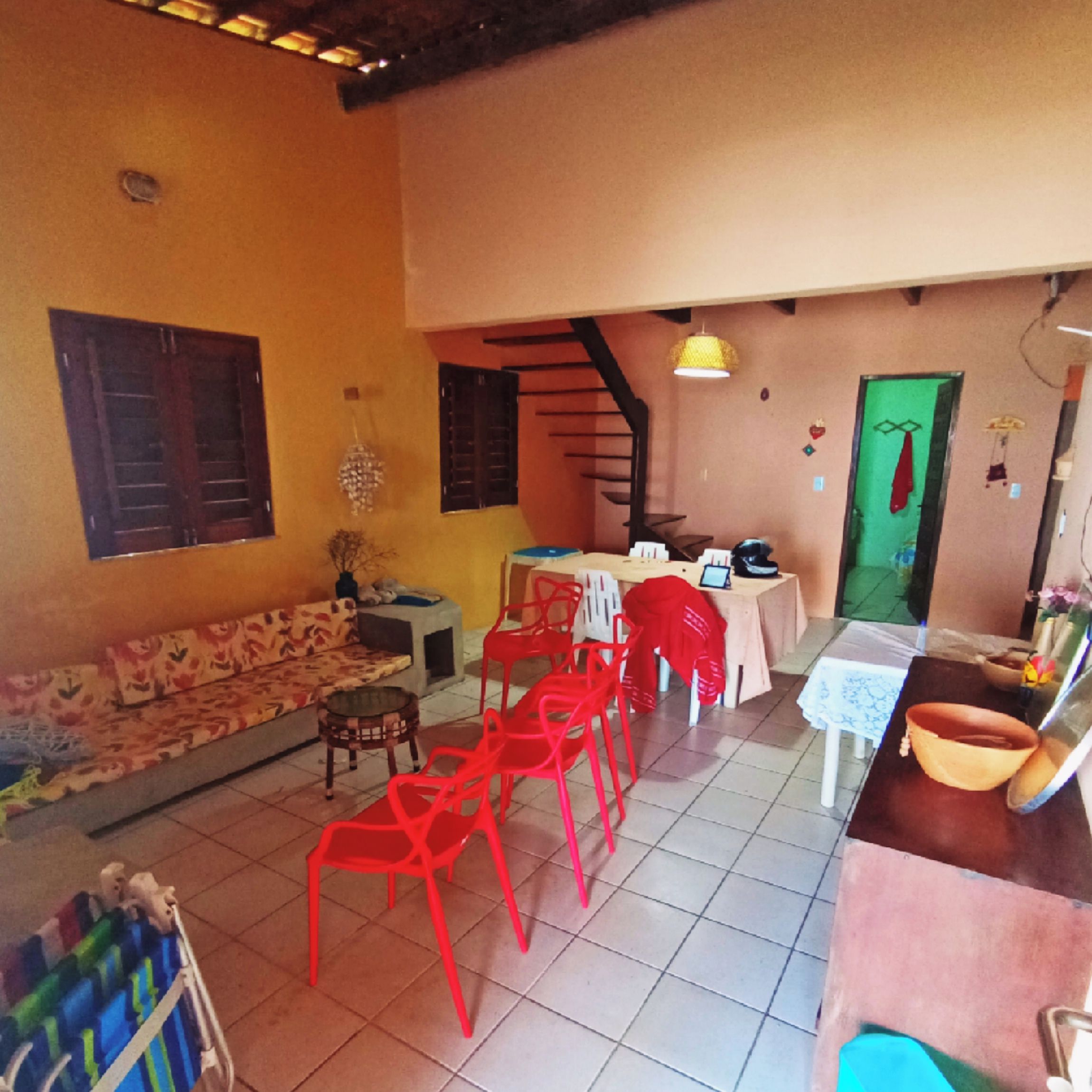 Une pièce comprenant un canapé, des fauteuils rouges, une table à manger et un escalier.
