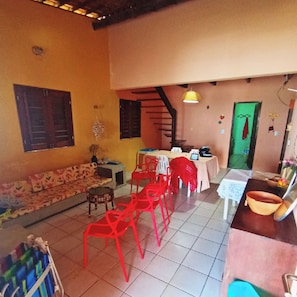 Una habitación con sofá, sillas rojas, una mesa de comedor y una escalera.