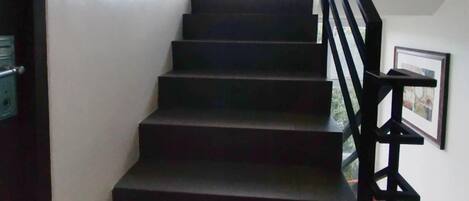 A staircase with a black handrail leading to a landing. A door with the number 302 is visible on the left.