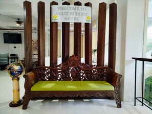A wooden sofa with a green cushion in front of a sign that reads "WELCOME TO SULIT BUDGET HOTEL". - Sulit Hotel Manila (San Juan)
