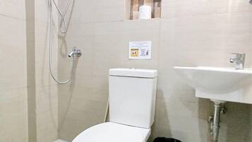 Un baño pequeño y limpio con inodoro, lavabo, ducha y espejo.