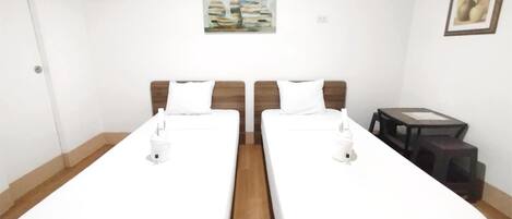 Una habitación de hotel con dos camas individuales, una mesita y un cuadro en la pared.
