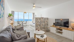 A modern living room with a sofa, a TV, a dining area, and a view of the sea. - Ocean Loka by Interhome (Callao Salvaje)