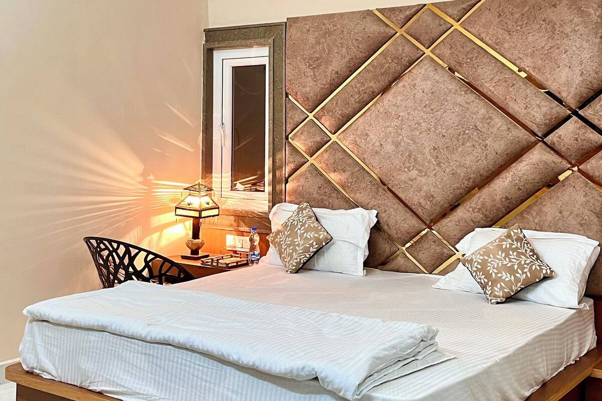 A bedroom with a bed, a ceiling fan, a nightstand, and a mirror.