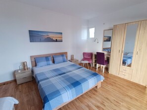 Une chambre à coucher avec un lit, une table de chevet, une chaise, une armoire et un tableau accroché au mur.