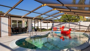 Piscina coberta com área de estar, mesa e cadeiras.