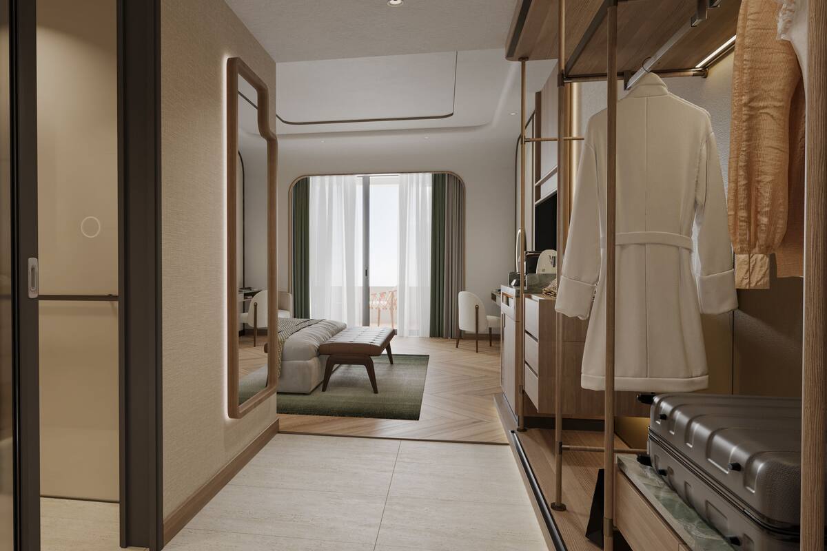 A hotel room with a bed, a desk, a chair, a mirror, and a wardrobe.