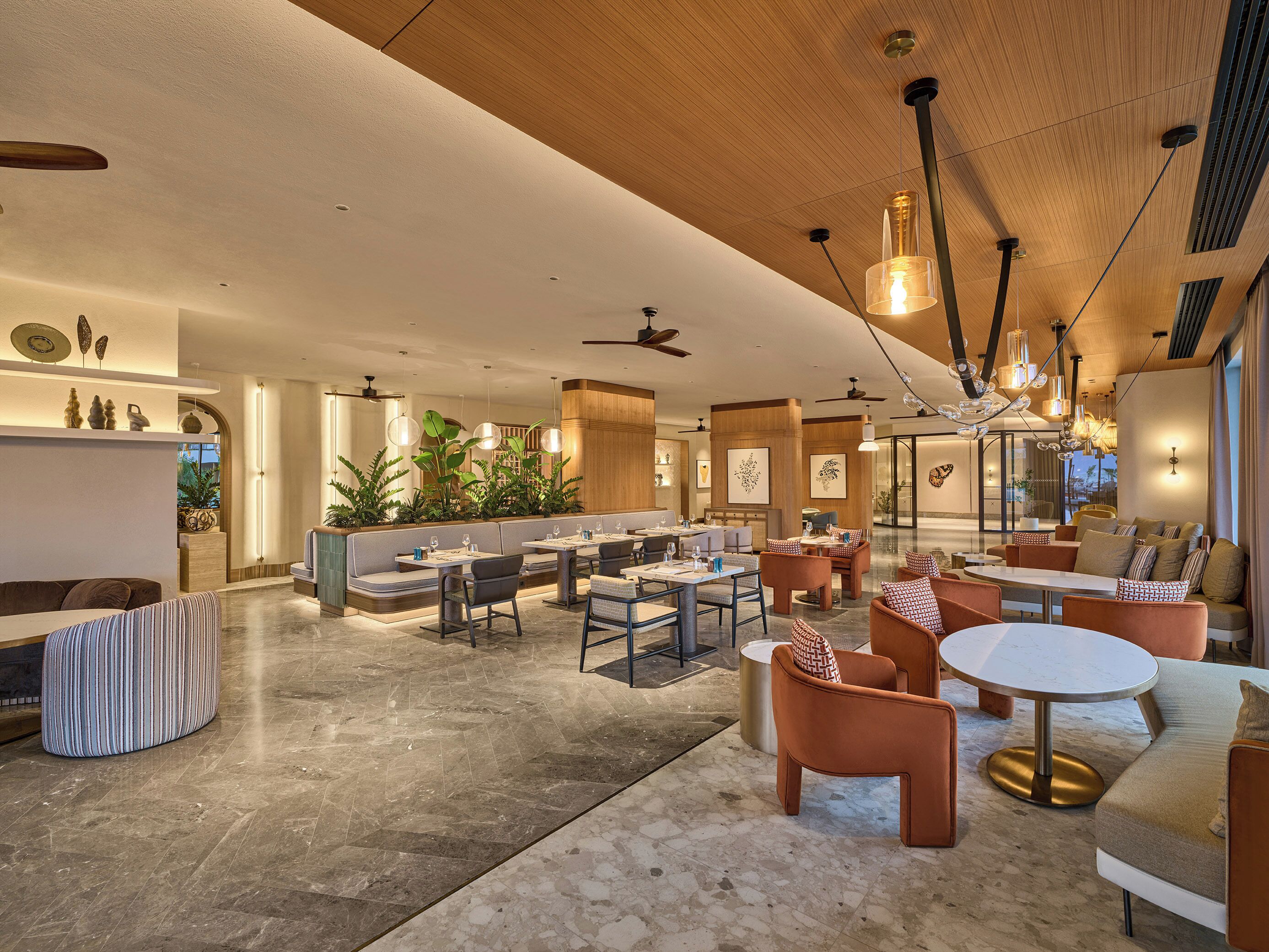 A spacious hotel lobby with seating areas, a reception desk, and a view of the outdoors.
