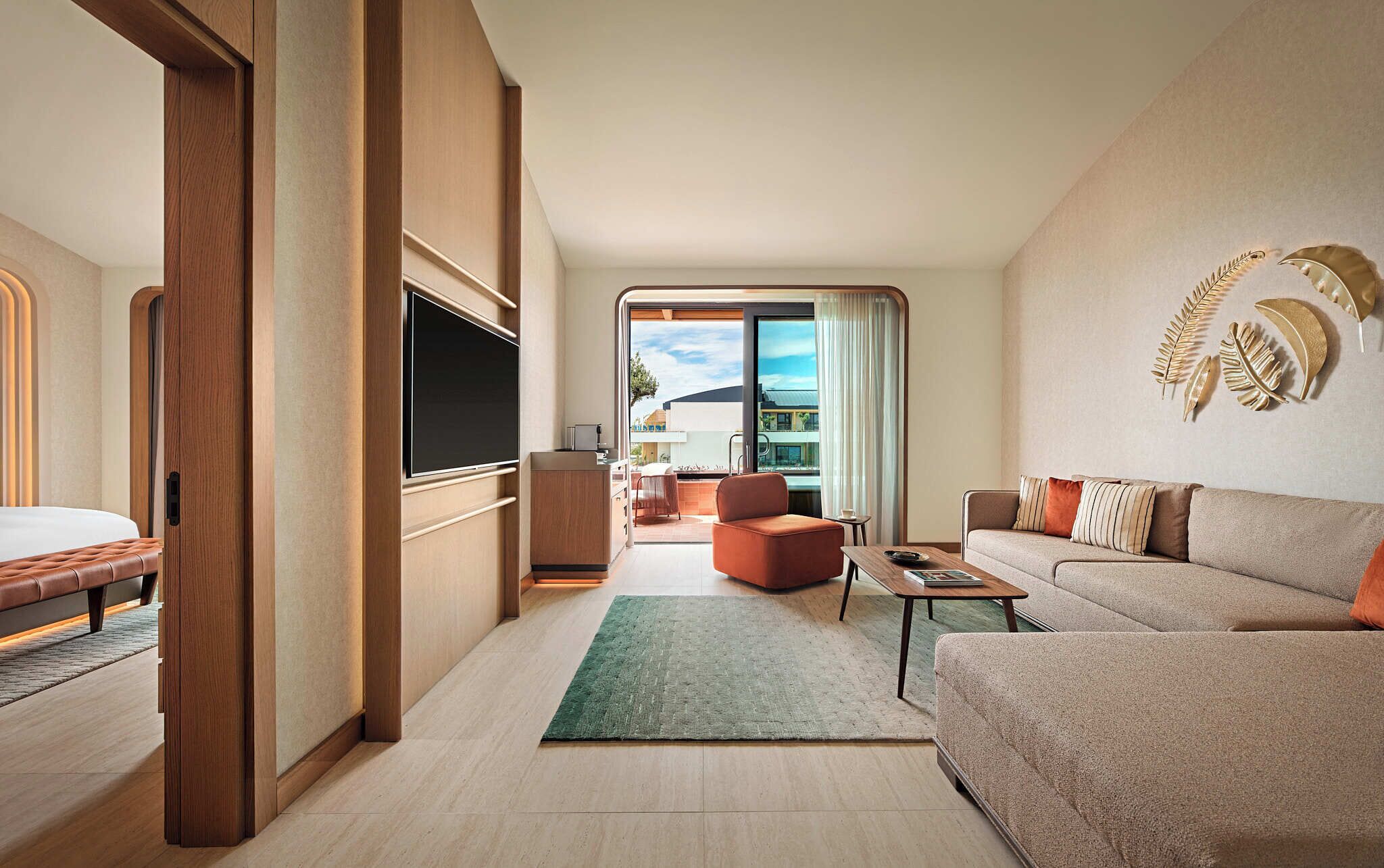 A modern hotel room with a bed, a TV, a sofa, a coffee table, and a view of the outside.