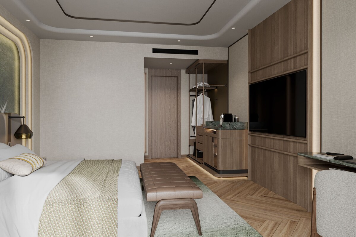 Una habitación de hotel moderna con una cama grande, un área de descanso, un tocador con espejo y una televisión.