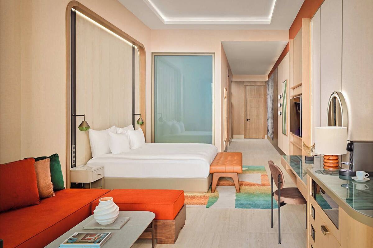A hotel room with a bed, a desk, a sofa, a coffee table, and a ceiling fan.