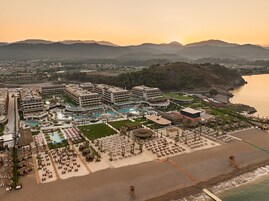 Um resort com várias construções, uma grande área de piscina e uma praia.