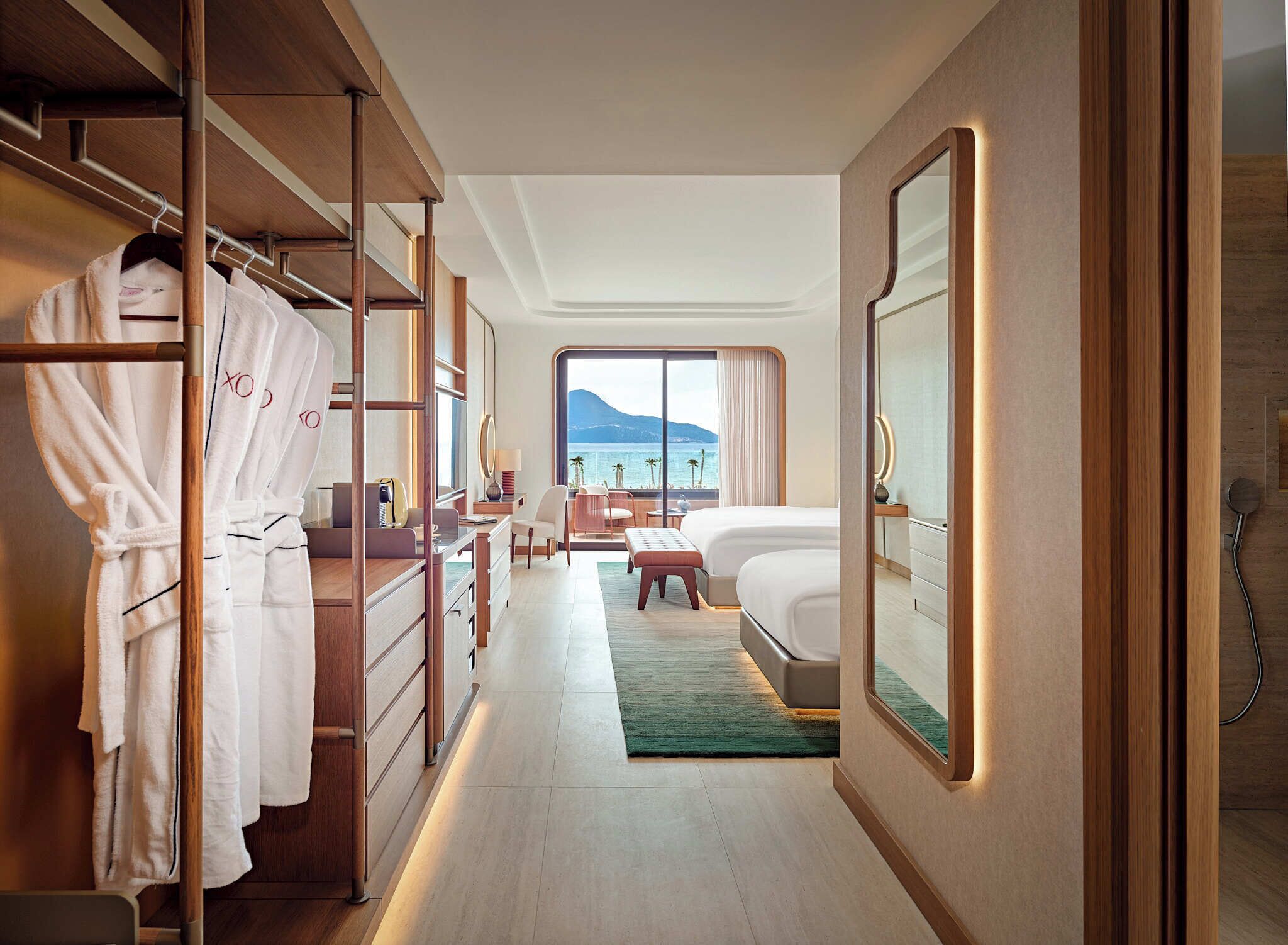 A hotel room with a walk-in closet, a bed with a view, a desk, and a chair.