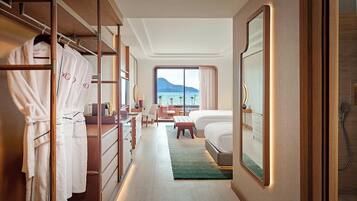 A hotel room with a walk-in closet, a bed with a view, a desk, and a chair.