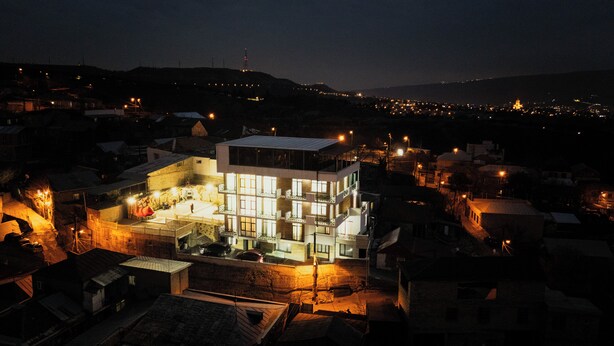 A modern multi-story building with a flat roof, surrounded by smaller houses. - Panorama David Apart-Hotel (T'bilisi)