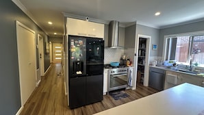 Una cocina moderna con un refrigerador negro, horno de acero inoxidable y ventana con vista a un muro de ladrillo.