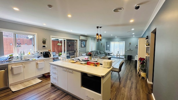 Una cocina moderna con una isla central, electrodomésticos integrados y un comedor con vista al salón.