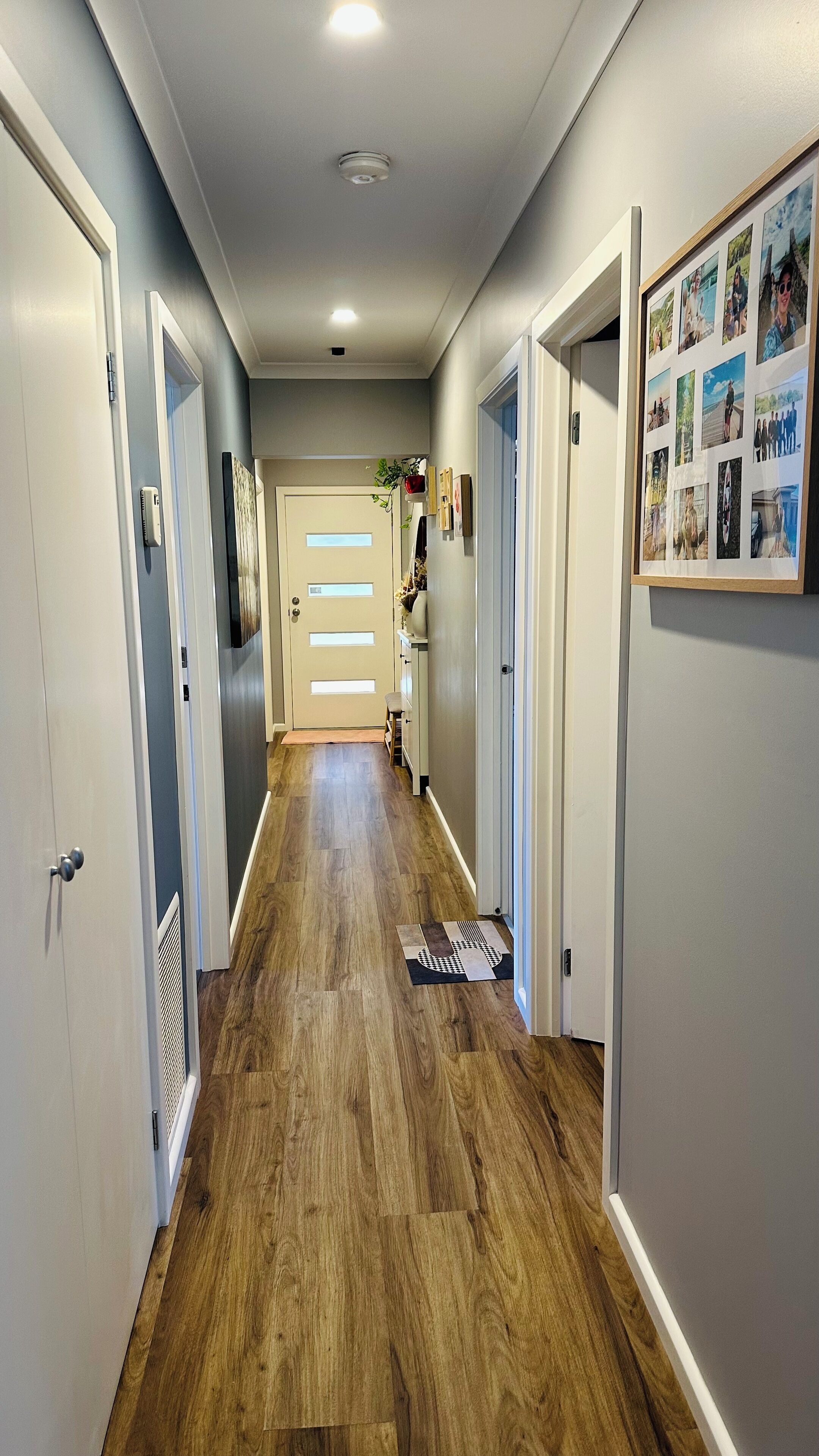 A hallway with wooden flooring, white walls, and a door at the end.