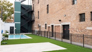A courtyard with a swimming pool, a brick building, and a staircase. - Gisele Hotel (New Orleans)