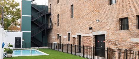 A courtyard with a swimming pool, a brick building, and a staircase.