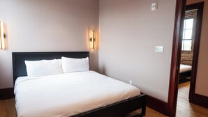 A neatly made bed in a room with a wooden floor and a brick wall. - Gisele Hotel (New Orleans)
