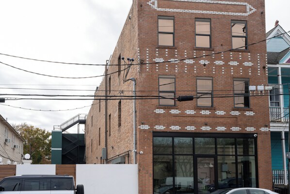 A multi-story brick building with a large glass storefront, multiple windows, and visible electrical wires. - Gisele Hotel (New Orleans)