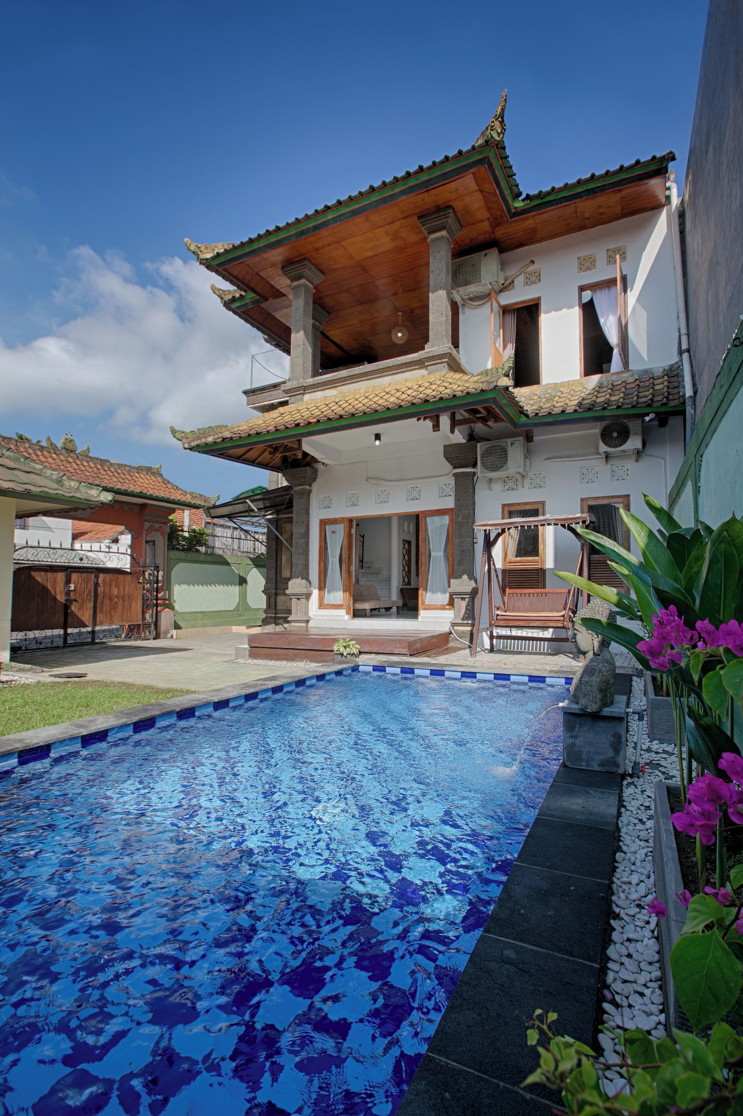Une maison traditionnelle dotée d’une piscine, d’une terrasse en bois et d’un espace extérieur aménagé et couvert.