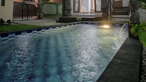 A traditional building with a swimming pool, wooden architecture, and a statue.