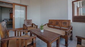 A wooden dining area with a table and chairs, a sofa, and a potted plant.