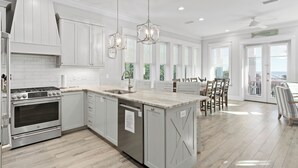 A spacious kitchen with a large island, stainless steel appliances, and pendant lighting.