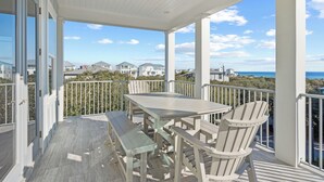 A covered outdoor area with a table and chairs, overlooking a coastal view.