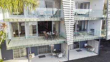 A modern two-story building with a glass balcony, outdoor seating, and a view of the surrounding area.