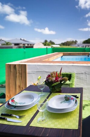 A table set outdoors with plates, glasses, and a floral centerpiece. - Nahi Loge, Welcome home (Vaitape)