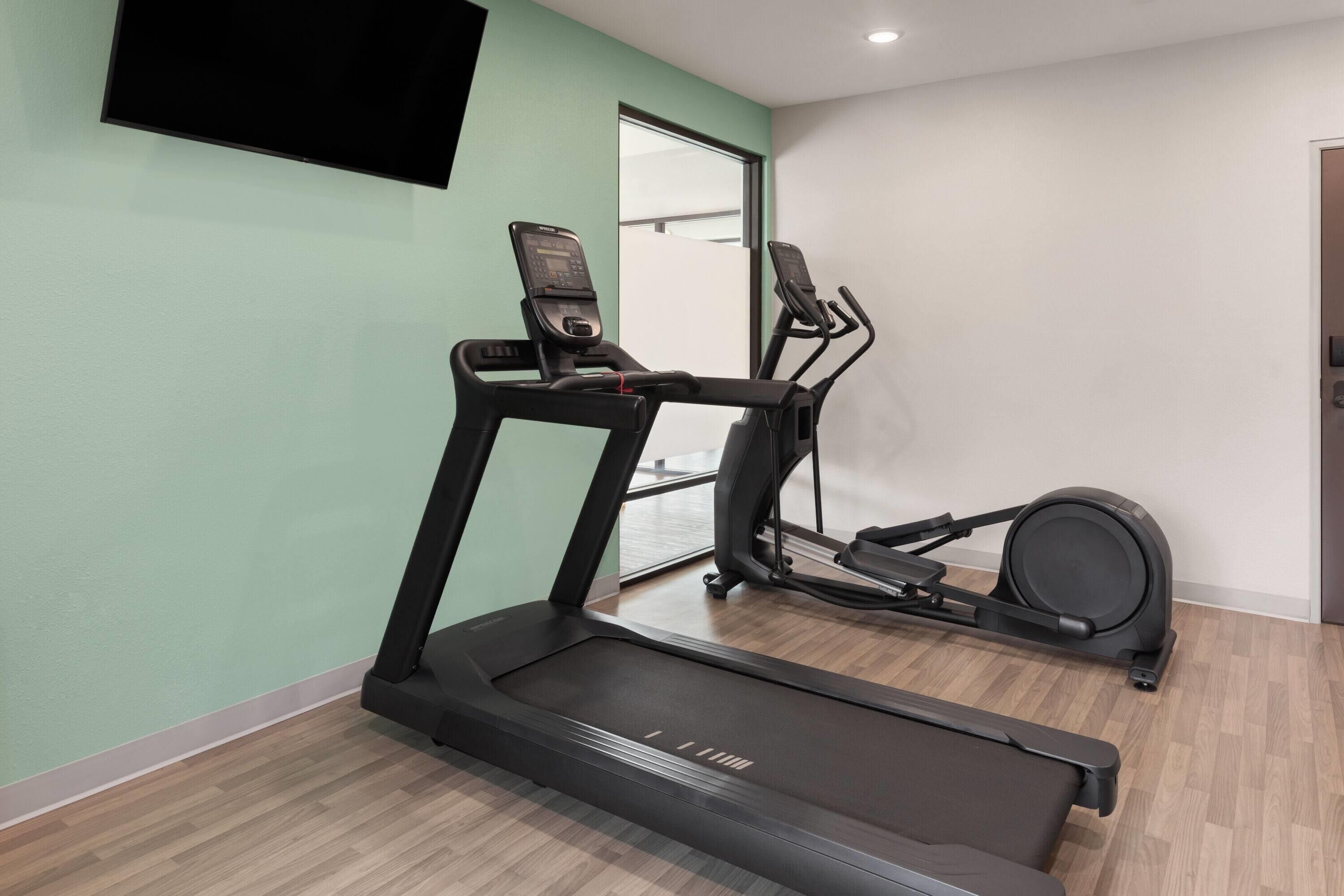 A home gym with a treadmill, elliptical, and stationary bike.