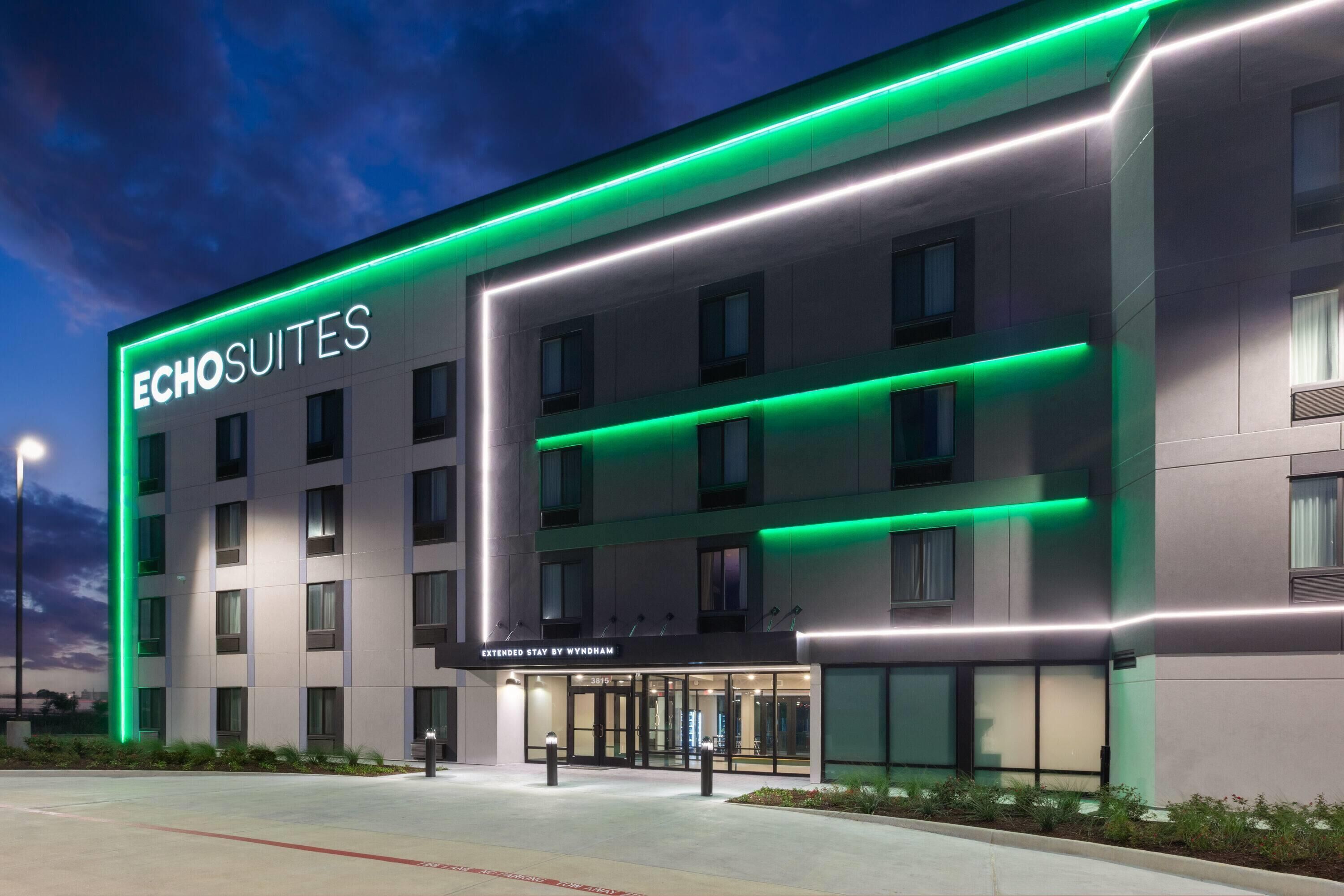 Un hotel con fachada moderna, varios pisos y una entrada destacada con puertas de vidrio.
