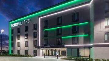 Un hotel con fachada moderna, varios pisos y una entrada destacada con puertas de vidrio.